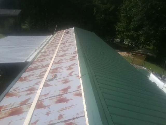 Old rusted panels beside newly installed green metal roofing — Wind Damage Roof Repair by Roofing Brothers in Talmo