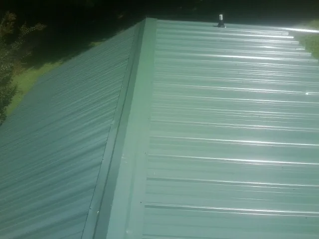 New green metal panels meeting at the ridge of a roof — Flat Roof Repair work by our crew in Talmo
