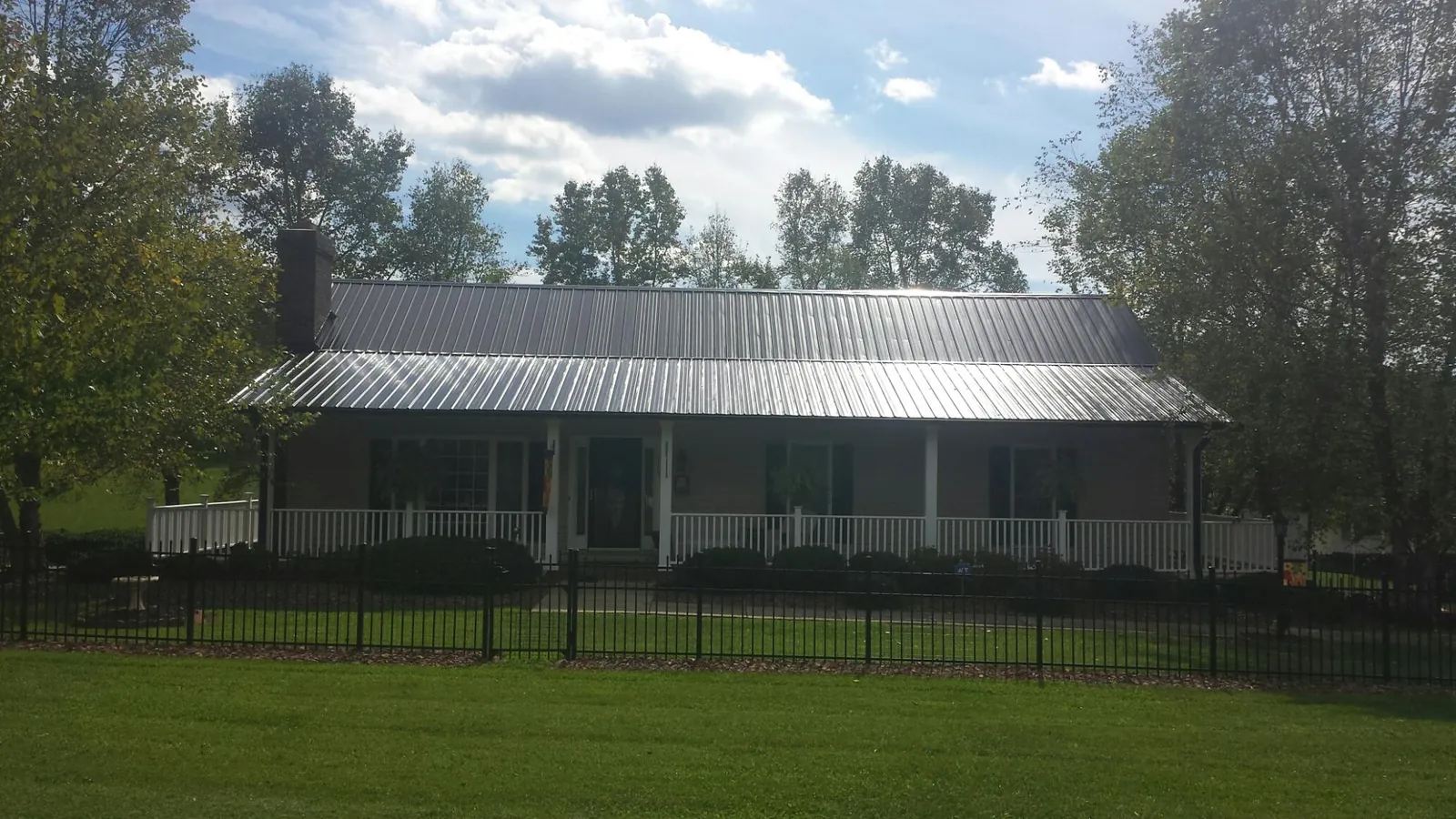 Gray metal roof on a brick ranch with a full width front porch — Gutter Guard Installation work by our crew in Talmo