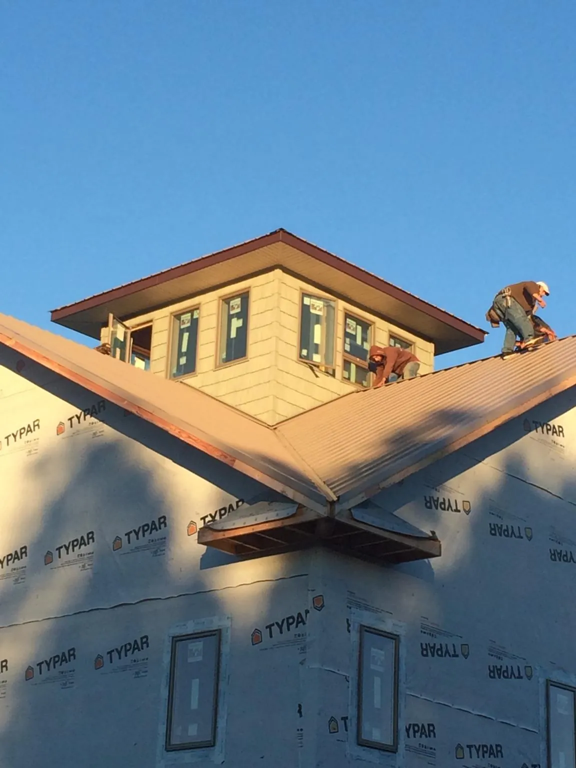 Roofers working around a rooftop cupola on a new metal roof at sunset — Roof Waterproofing in Talmo by Roofing Brothers